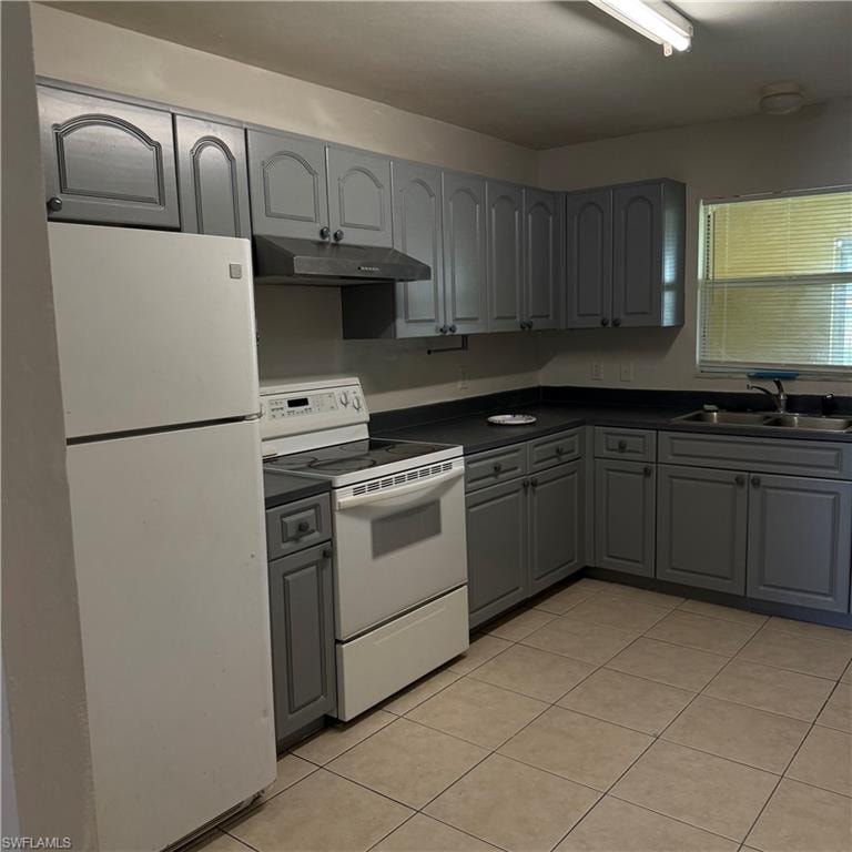 Kitchen featuring gray cabinetry with brushed nickel hardware, dark countertops, and tile flooring