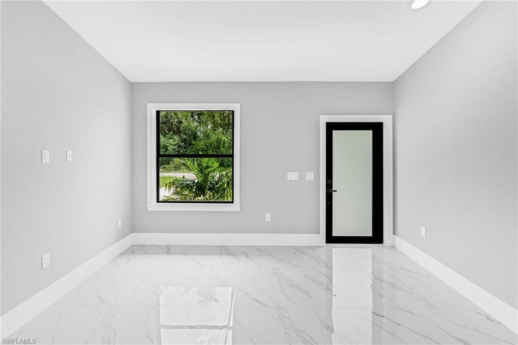Kitchen featuring white and gray cabinetry, stainless steel appliances, light-toned countertops, vaulted ceiling, and large format tile flooring