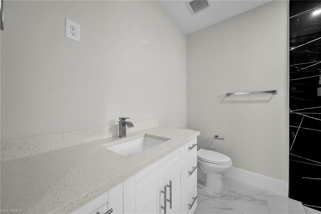 White vanity with integrated sink, speckled stone countertop, and contemporary chrome faucet