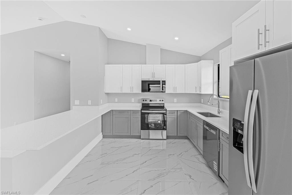 Modern kitchen featuring two-tone cabinetry, stainless steel appliances, a stainless steel sink with a gooseneck faucet, light-toned countertops, and marble-finish tile flooring
