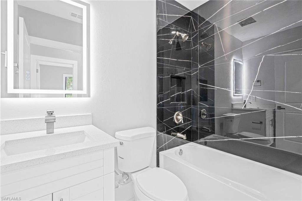 Shower featuring black tile with white veining, a built-in niche, a window, and hexagonal floor tile