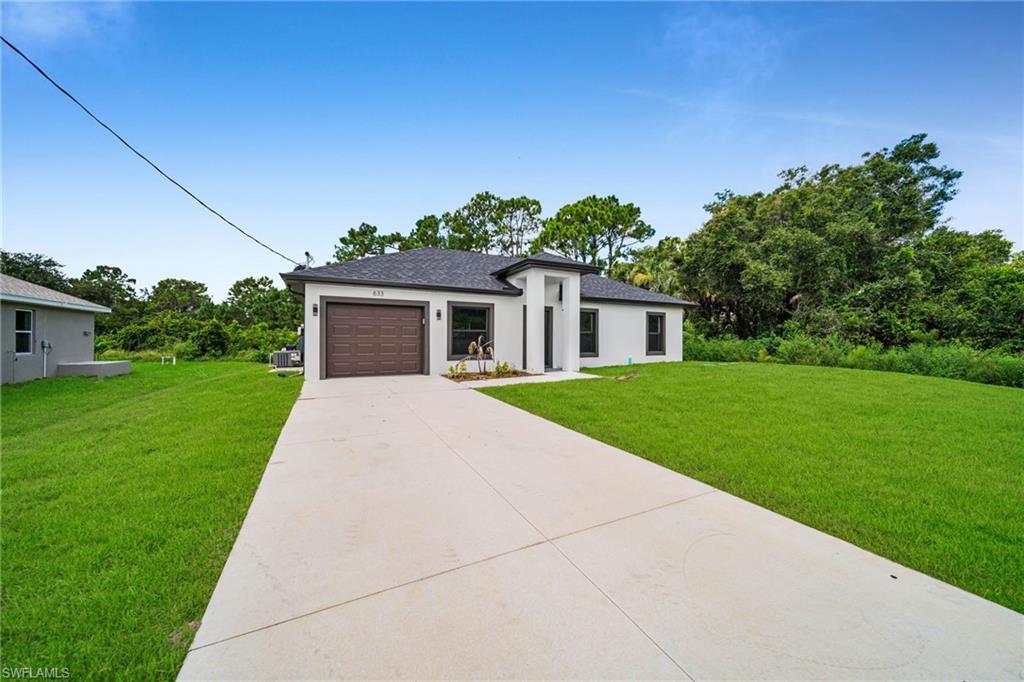 Contemporary exterior with a dark-pitched roof, white stucco facade, and a brown paneled garage door