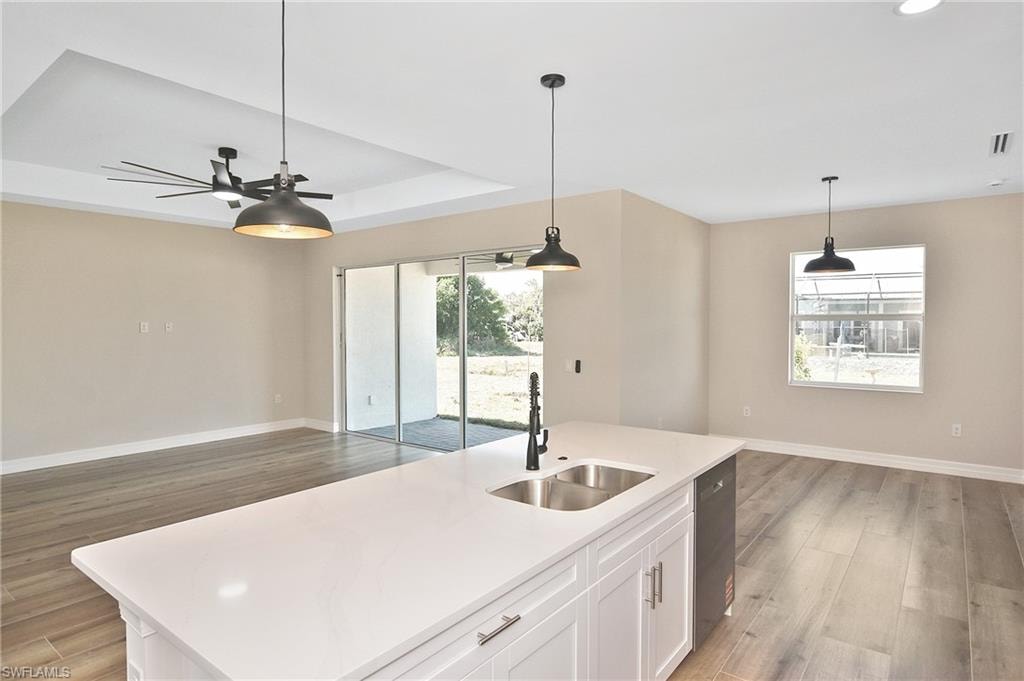 Kitchen island featuring a double basin stainless steel sink with a matte black faucet, and white cabinetry