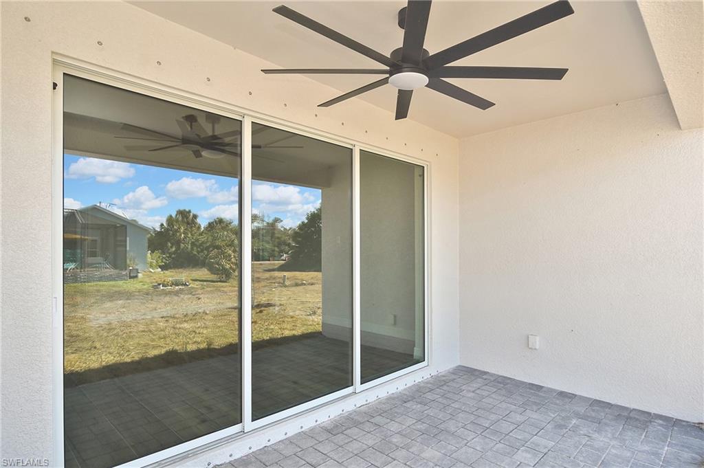Covered patio featuring paver flooring, a ceiling fan with integrated lighting, and a large sliding glass door
