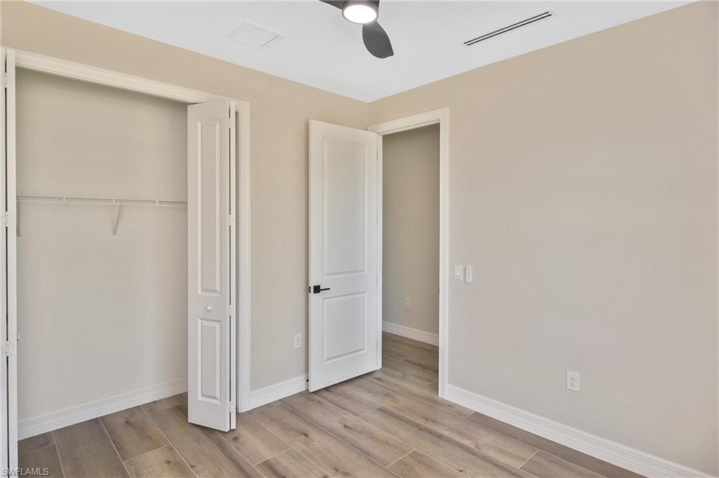 Room featuring wood-finish tile flooring, a modern ceiling fan, bi-fold closet doors, and a paneled interior door with matte black hardware