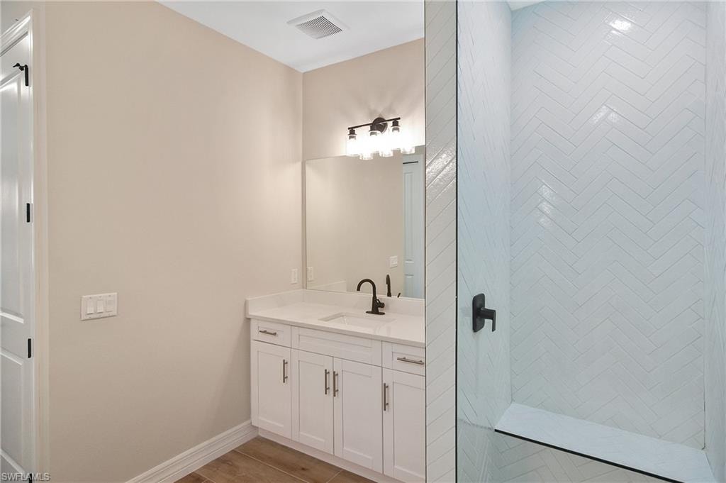 Bathroom featuring a white vanity with a light-toned countertop, a recessed sink, and matte black fixtures