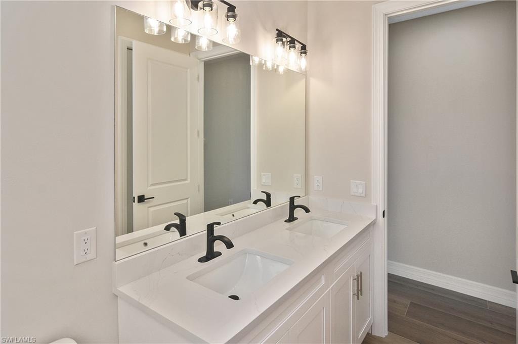 Dual vanity with white cabinetry, quartz countertop, and matte black fixtures