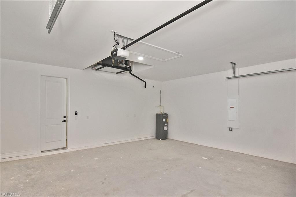 Spacious garage with concrete flooring, white painted walls, overhead garage door track system, and built-in water heater