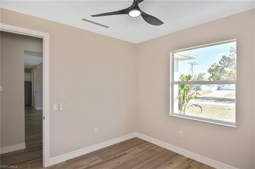 Neutral-toned room featuring wood-finish flooring and white baseboards