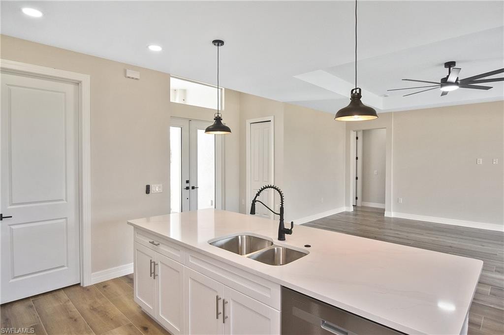 Kitchen island featuring a double-basin sink, gooseneck faucet, and integrated dishwasher