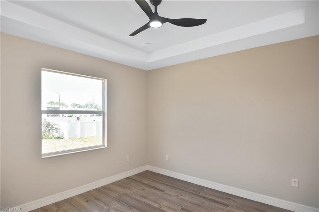 Wood-finish flooring and tray ceiling featuring a modern ceiling fan