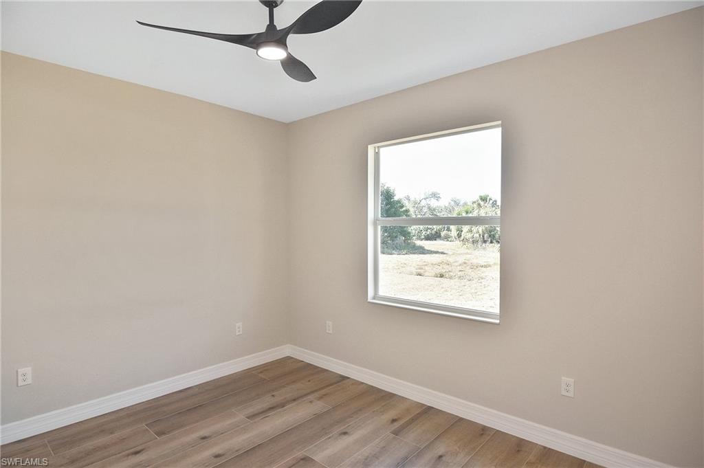 Room featuring wood-finish flooring, a modern ceiling fan with integrated lighting, and a window with a white frame