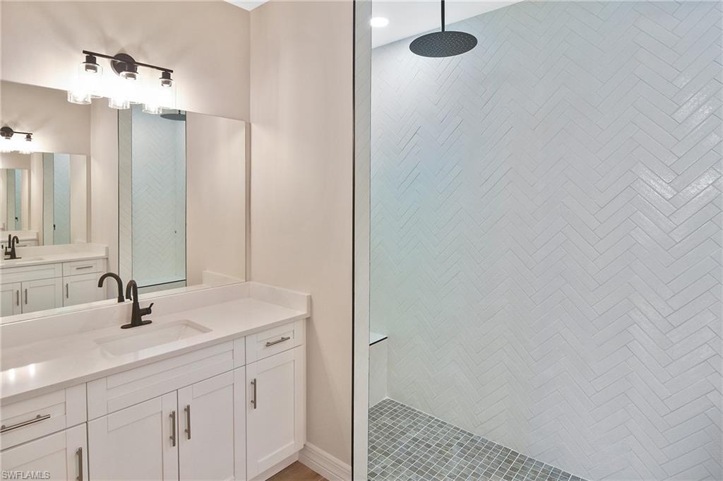 Modern bathroom featuring a white vanity with integrated sink, matte black faucet, and a large mirror