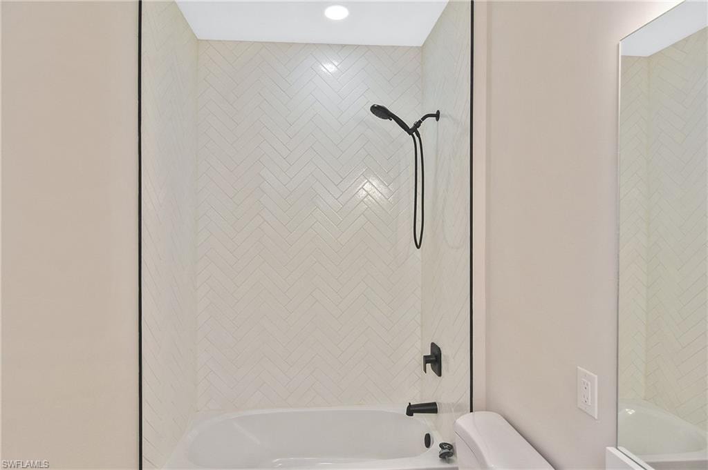 Modern shower/tub combination featuring white subway tile in a herringbone pattern