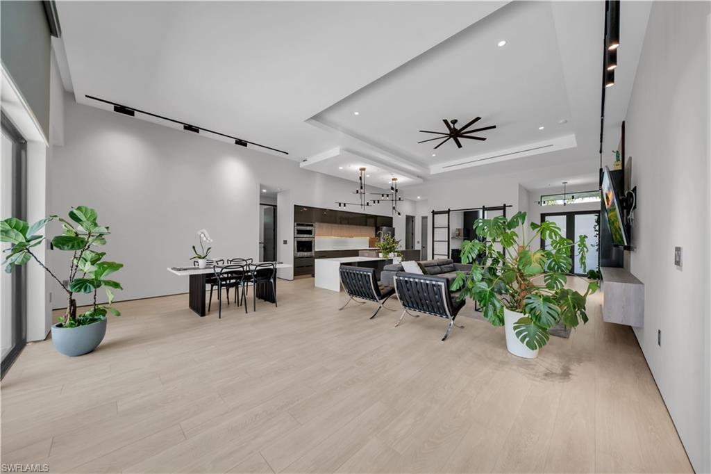 Open-concept living area featuring light wood-finish flooring, vaulted ceilings, and recessed lighting