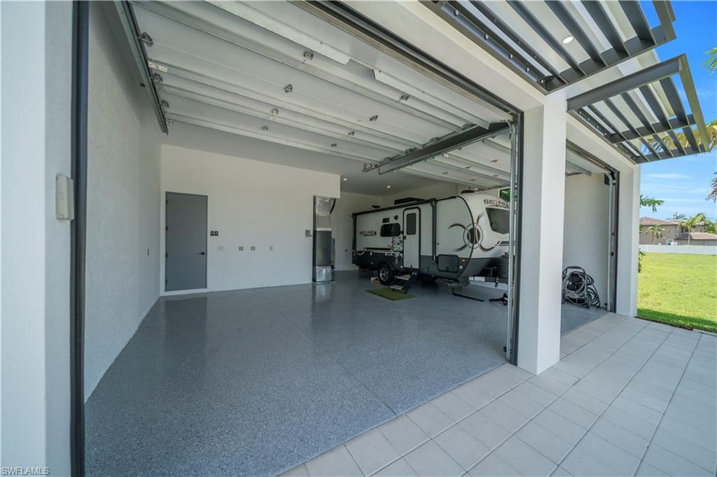 Spacious garage featuring a speckled epoxy floor, multiple overhead doors, and a side access door