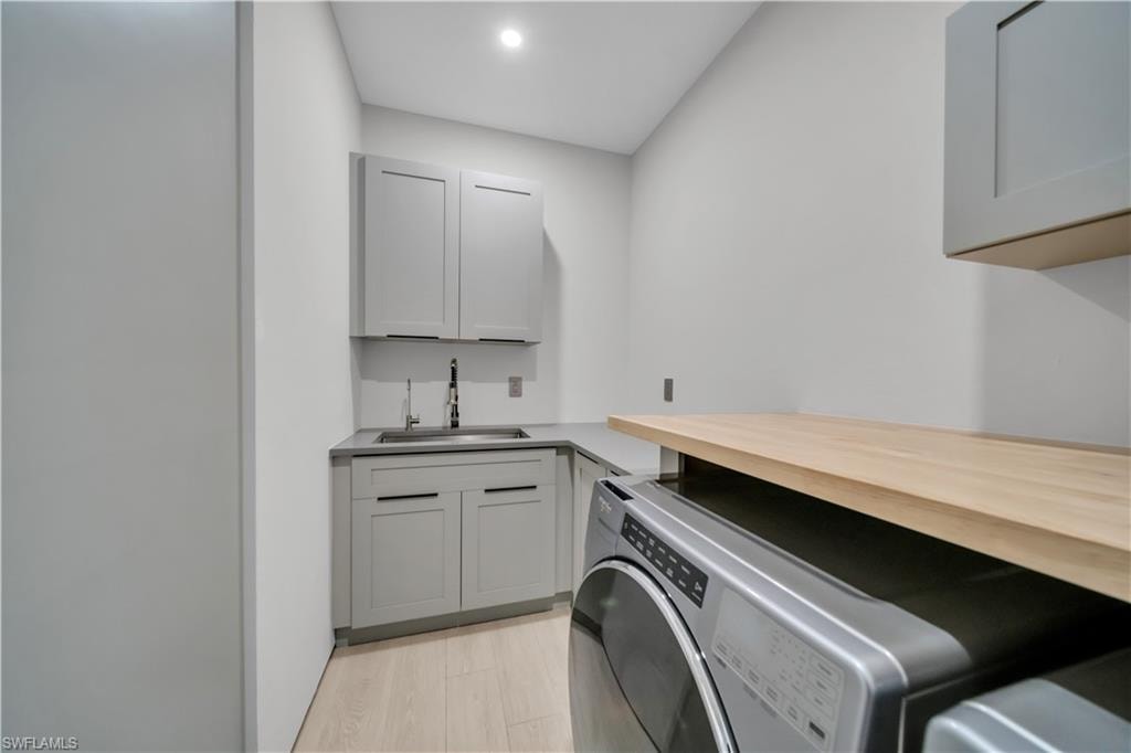 Dedicated laundry area featuring light wood-finish flooring