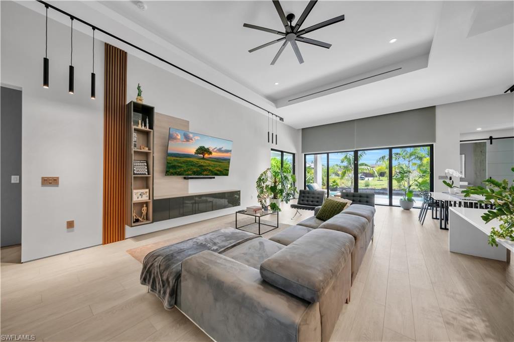 Spacious open-concept living area featuring light wood-finish flooring, a contemporary ceiling fan, and recessed lighting