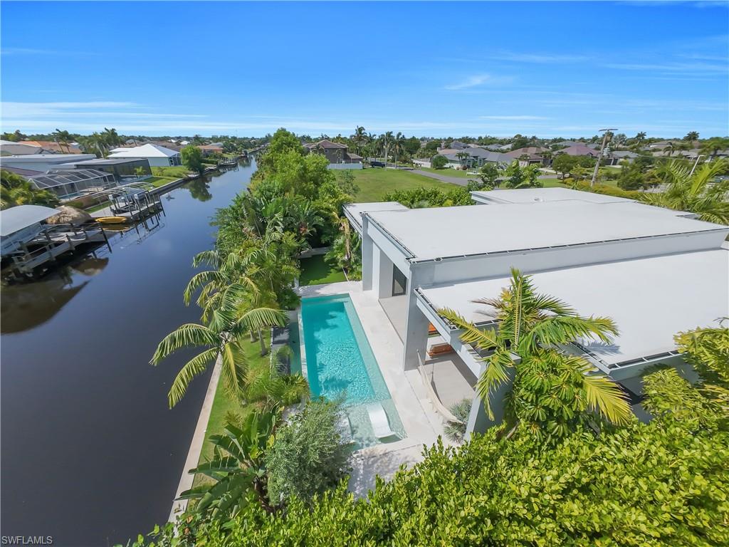 Waterfront property featuring a contemporary flat-roof architectural style and an elongated swimming pool with an integrated lounge area