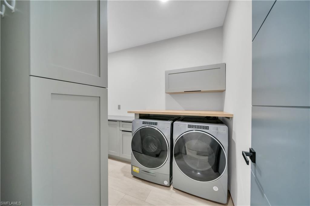 Dedicated laundry space featuring stacked appliances, light wood-finish countertop, and ample built-in cabinetry with shaker-style doors