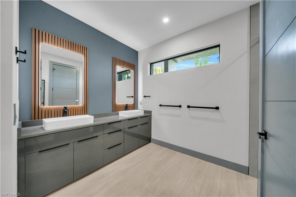 Double vanity featuring a long floating cabinet with multiple storage drawers, dual rectangular vessel sinks, and wood-finish flooring