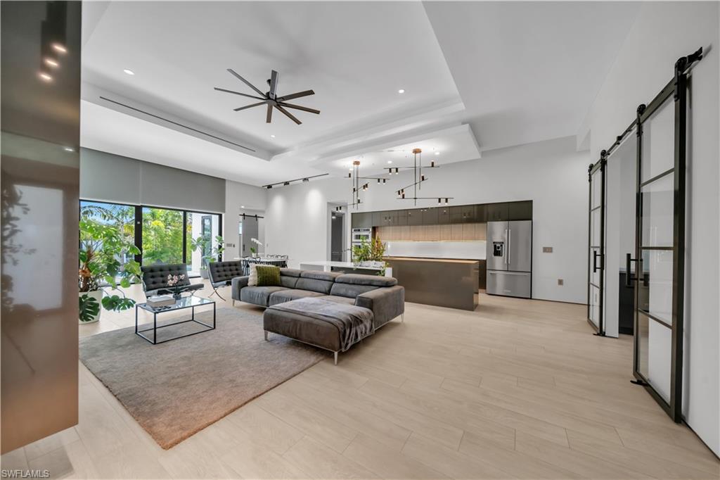 Open-concept living area featuring light wood-finish flooring and a tray ceiling
