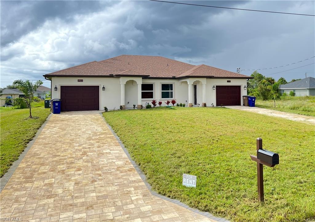 Duplex property featuring a neutral stucco exterior with contrasting brown garage doors and a coordinating shingle roof