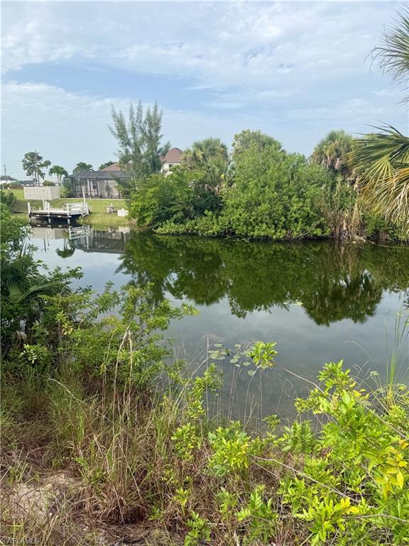 Waterfront property featuring a private boat dock with pilings, a calm canal, and lush tropical foliage