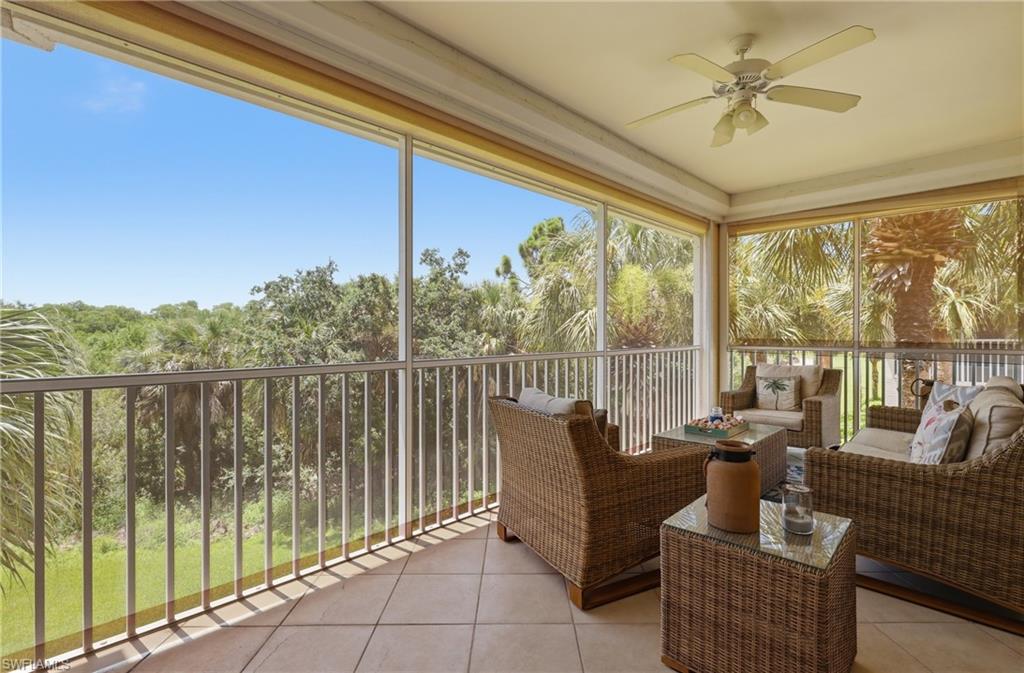 Screened balcony featuring a ceiling fan, light-toned tile flooring, and a metal railing