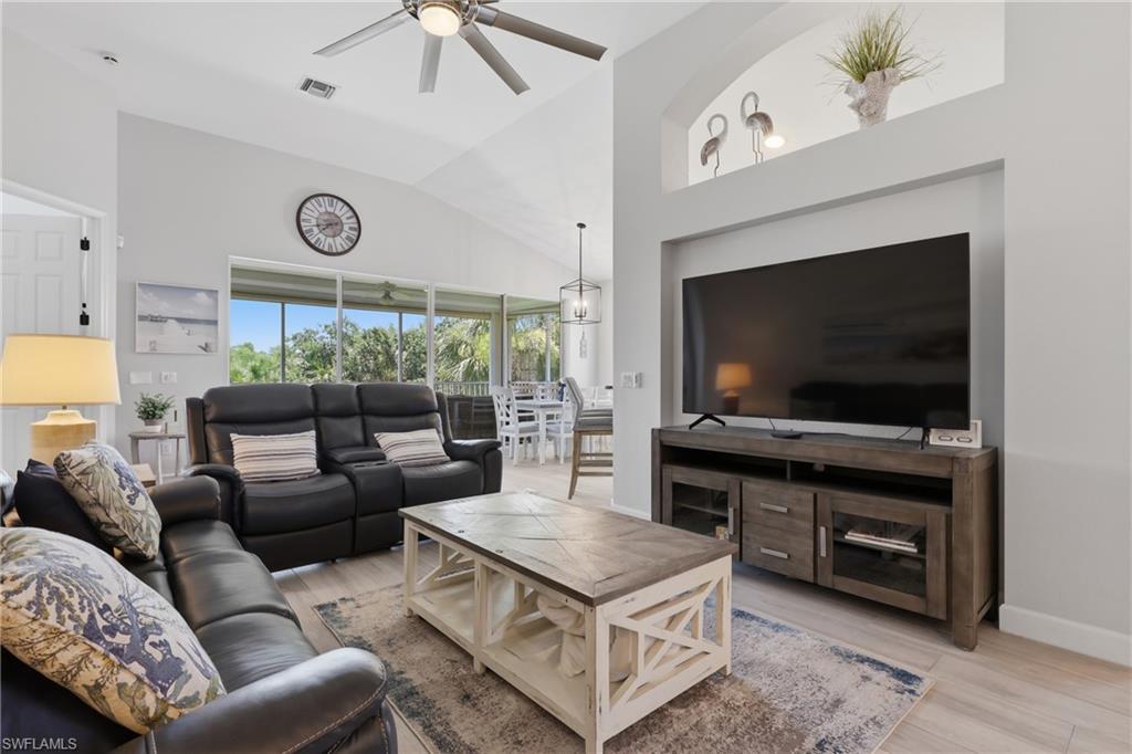 Vaulted ceilings with a ceiling fan, wood-finish flooring, and a built-in media niche with an arched display shelf