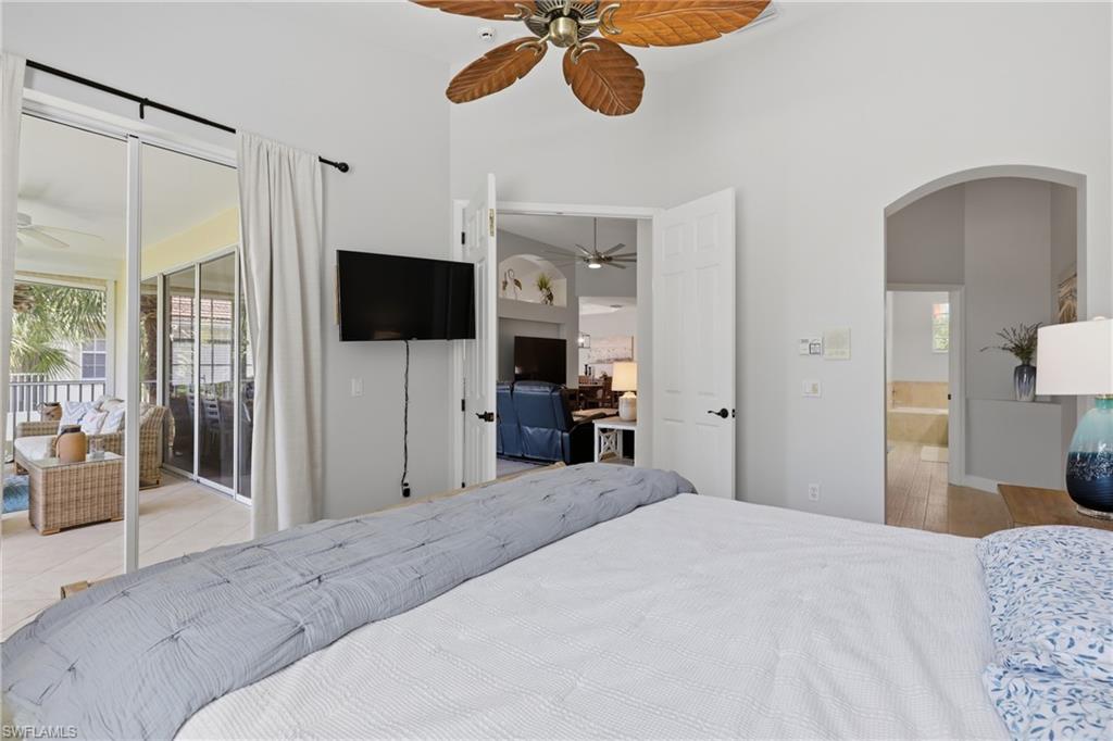 Vaulted ceiling room with an overhead fan, featuring large glass sliding doors opening to a screened-in patio