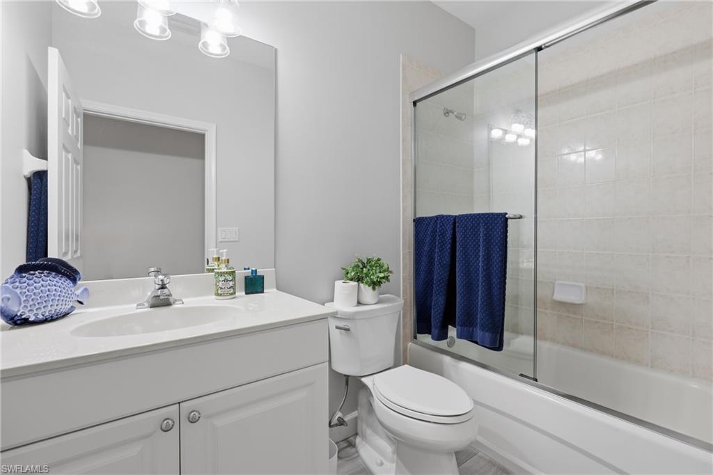 Bathroom featuring a white vanity with an integrated sink, polished chrome faucet, and a large wall mirror