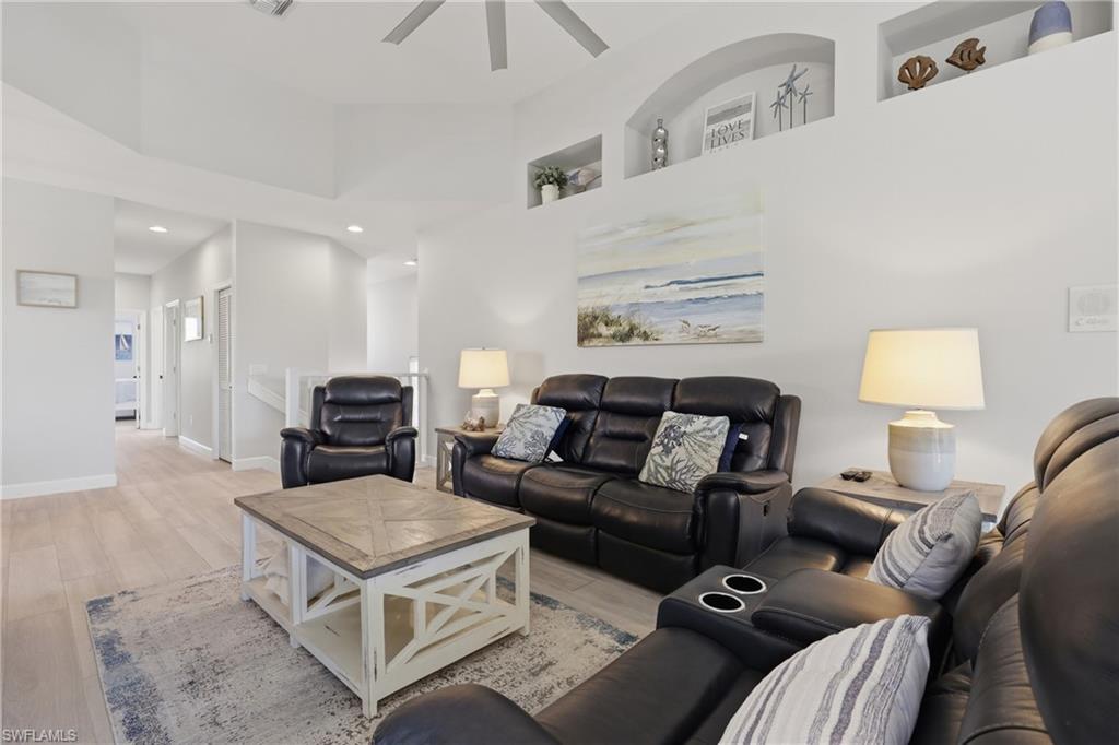 Vaulted ceiling living area featuring light wood-finish flooring, recessed lighting, and integrated wall niches
