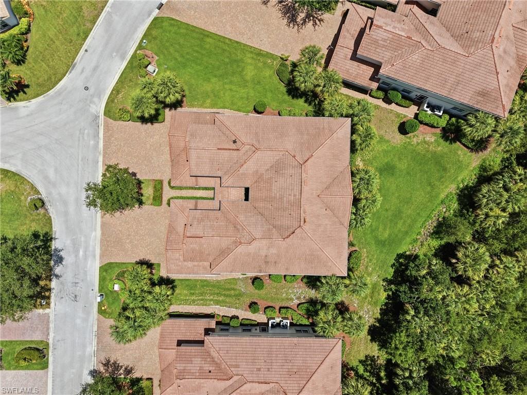 Expansive property featuring a multi-gabled tile roof, a brick paver driveway, and mature landscaping