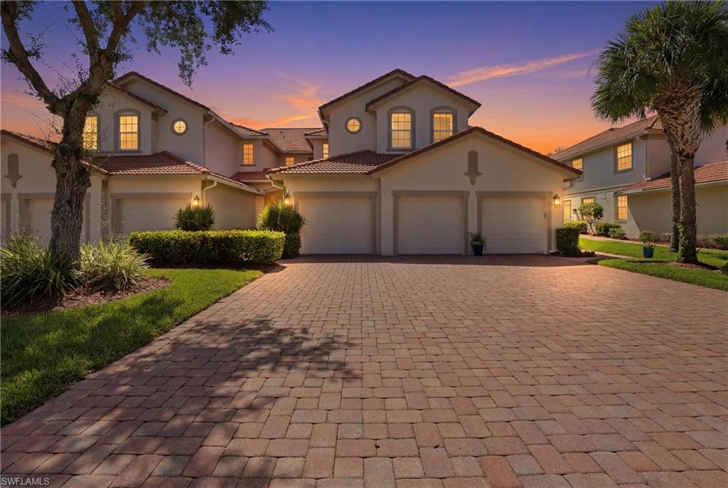 Paver driveway leading to a row of residences featuring barrel tile roofs, stucco exteriors, attached garages, and circular accent windows
