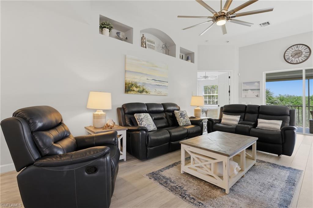 Living area with light wood-finish flooring, vaulted ceilings, and recessed architectural shelving
