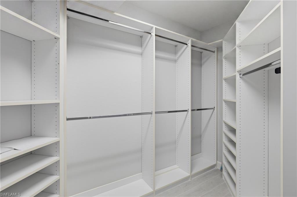 Custom closet system featuring white shelving, multiple hanging rods, corner shelving, and integrated shoe racks