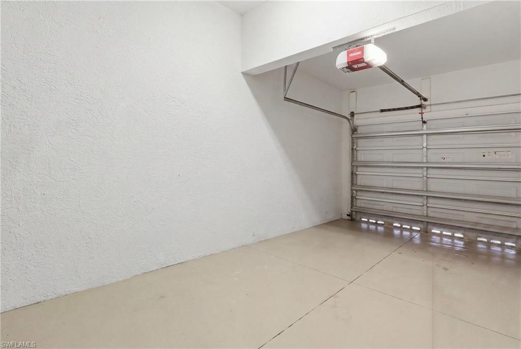 Single-car garage with a light-toned concrete floor, textured white walls, and an automatic garage door opener