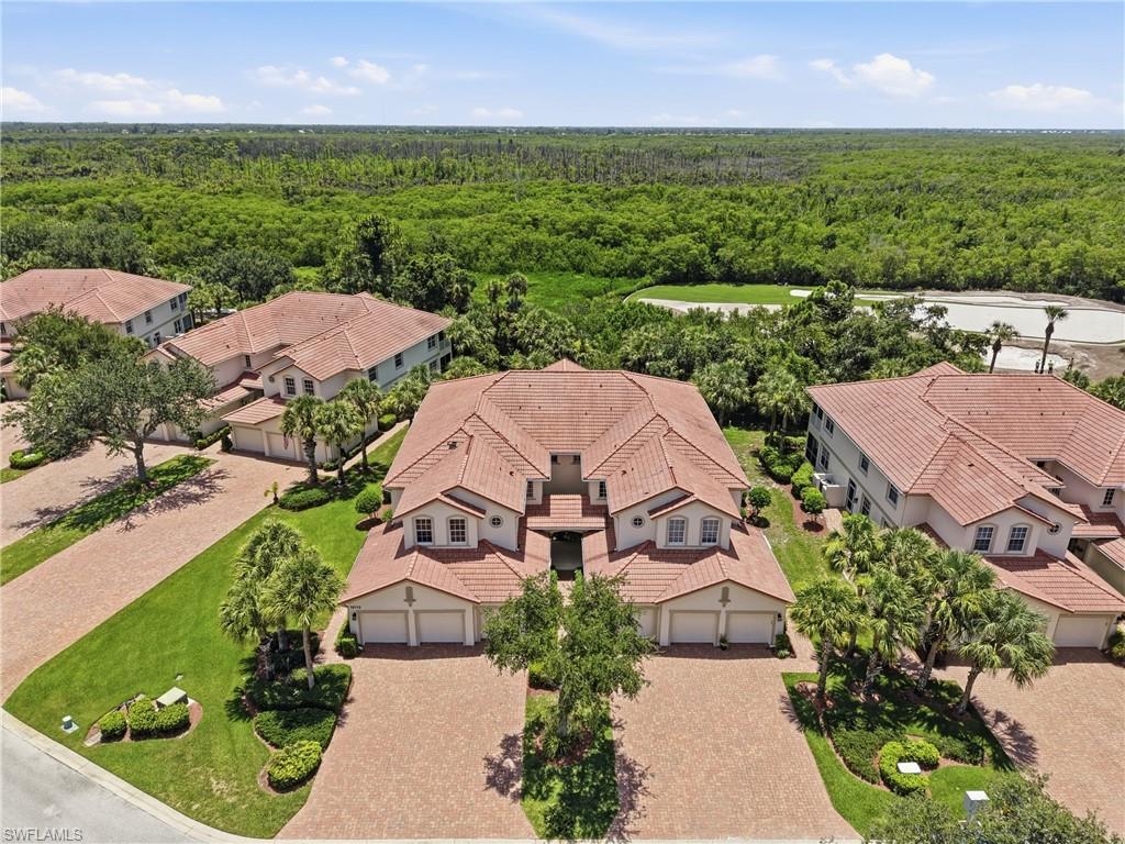 Aerial perspective showcasing multiple properties with red tile roofs, paver driveways, and lush landscaping