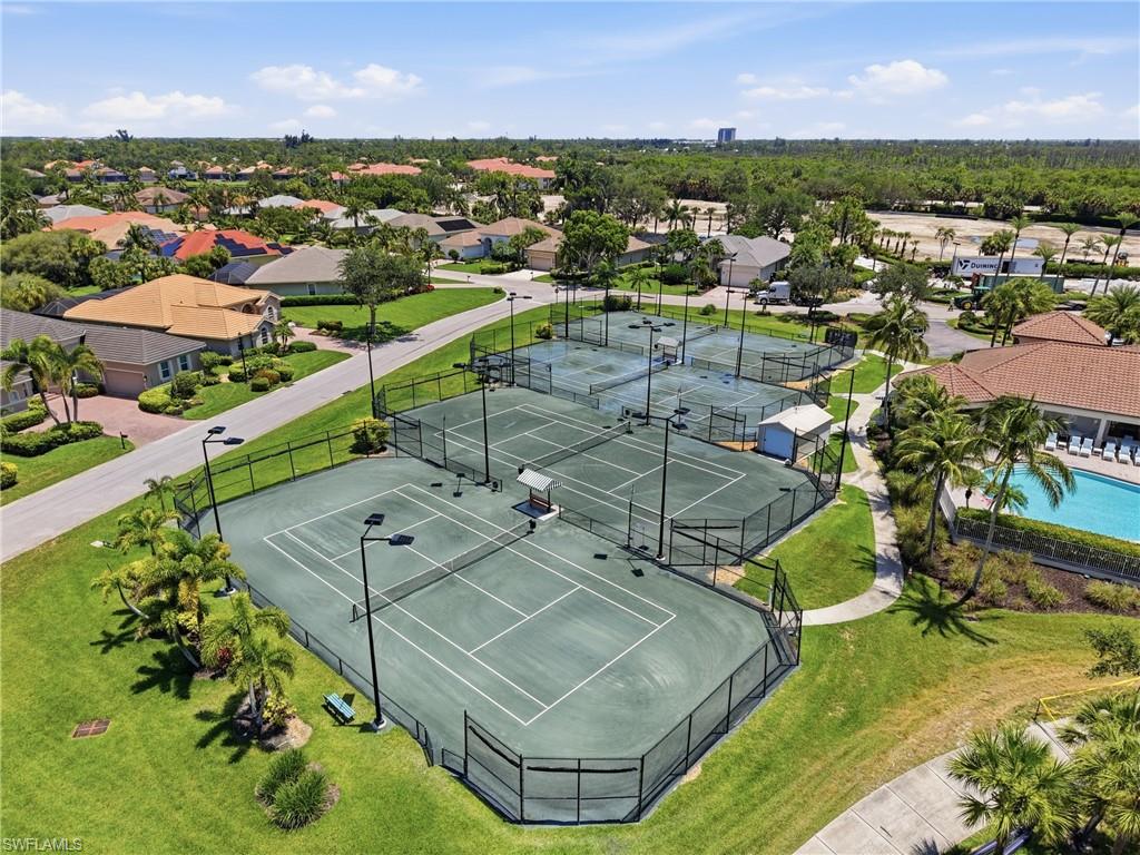 Multiple tennis courts with green hard surfaces, black fencing, and integrated lighting