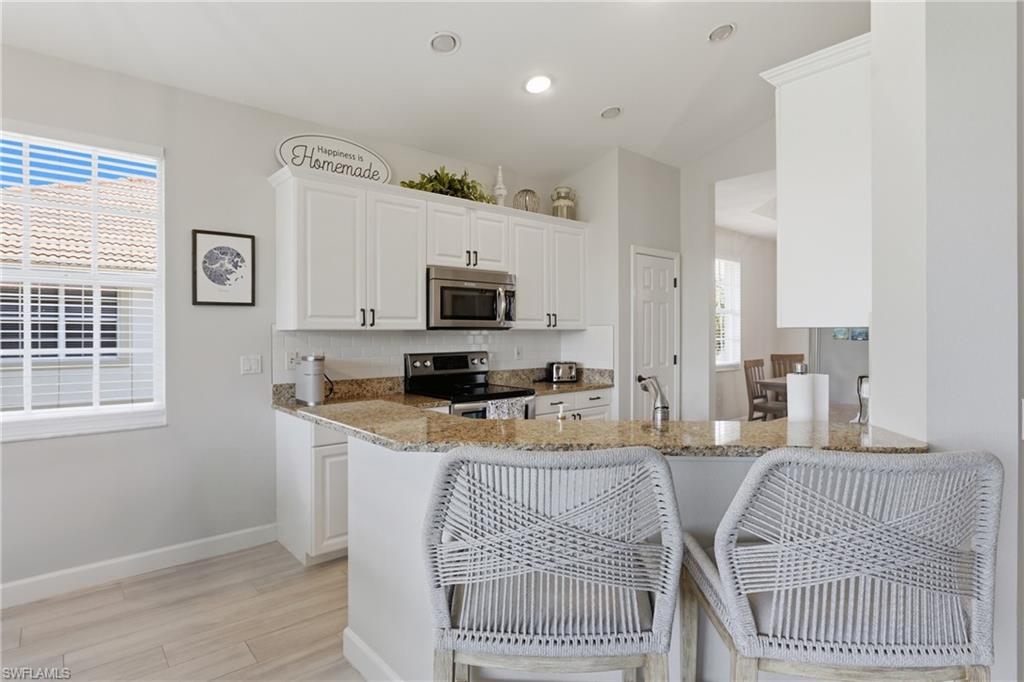 Kitchen featuring white cabinetry, stainless steel appliances, granite countertops, and a subway tile backsplash
