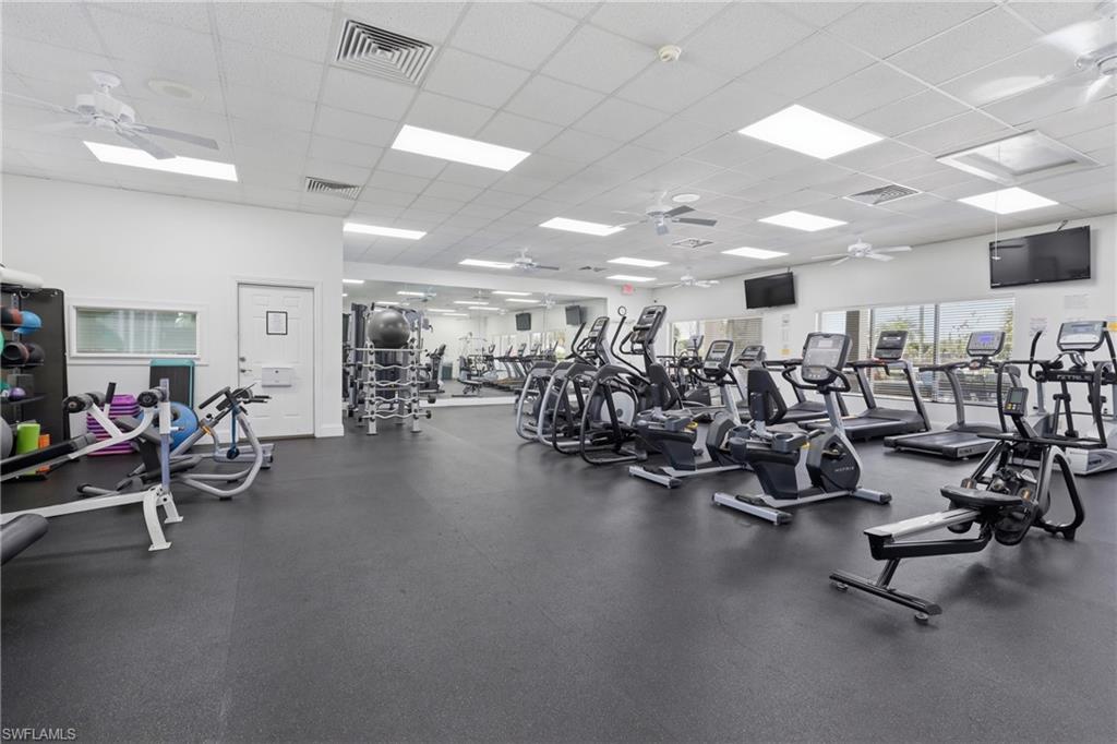 Spacious fitness room featuring extensive exercise equipment, rubberized flooring, ceiling fans, recessed lighting, and large exterior windows