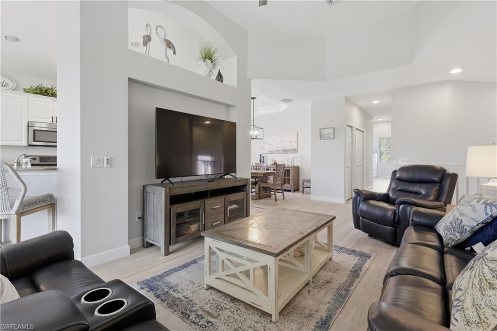 Open-concept living area featuring light wood-finish flooring, recessed lighting, and a tray ceiling