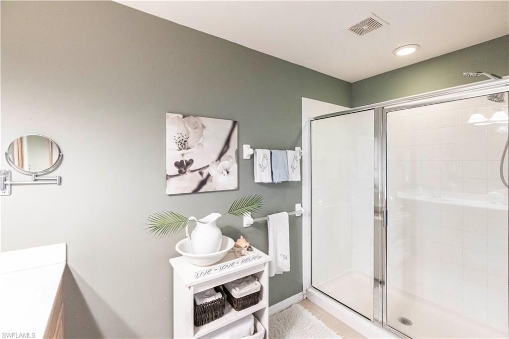 Full bath with a stall shower, vanity, and tile patterned flooring
