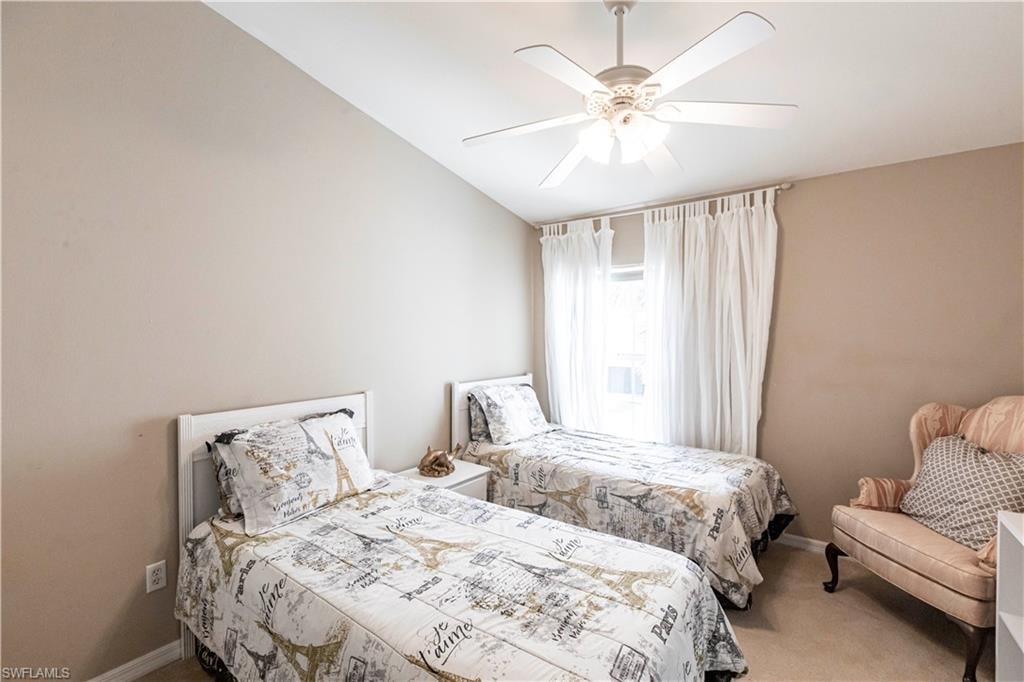 Carpeted bedroom featuring ceiling fan and vaulted ceiling