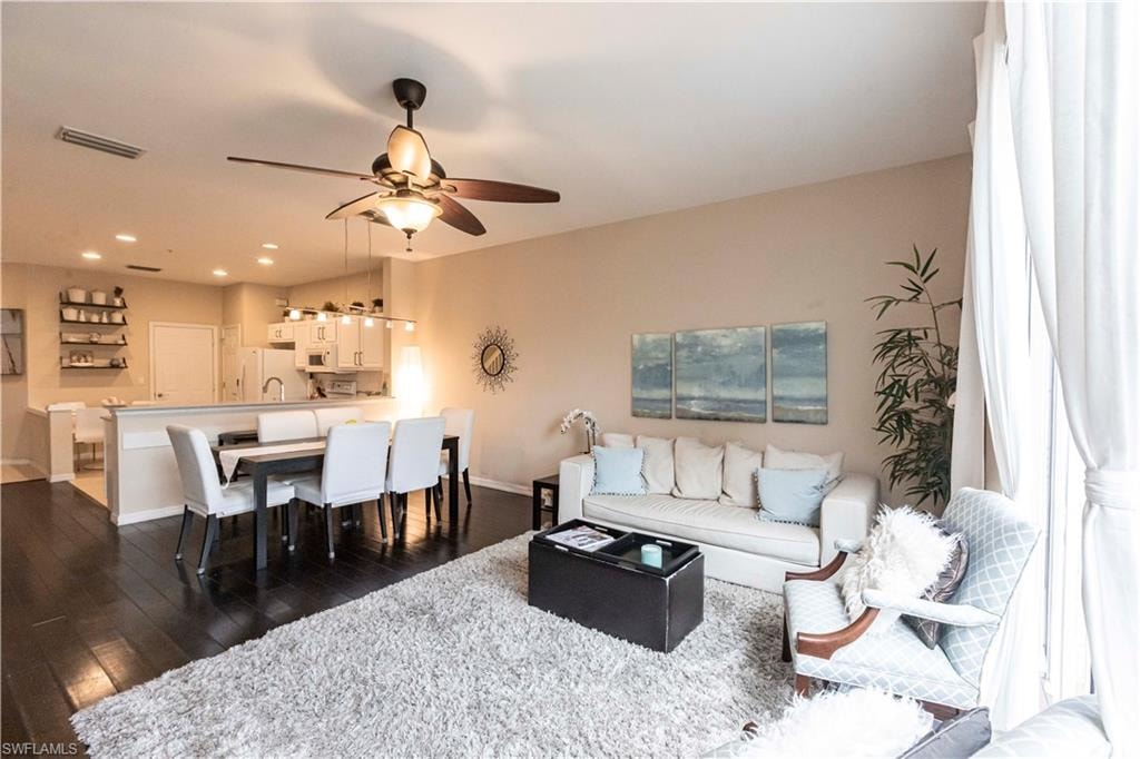 Living room with dark wood-type flooring, a ceiling fan, and recessed lighting