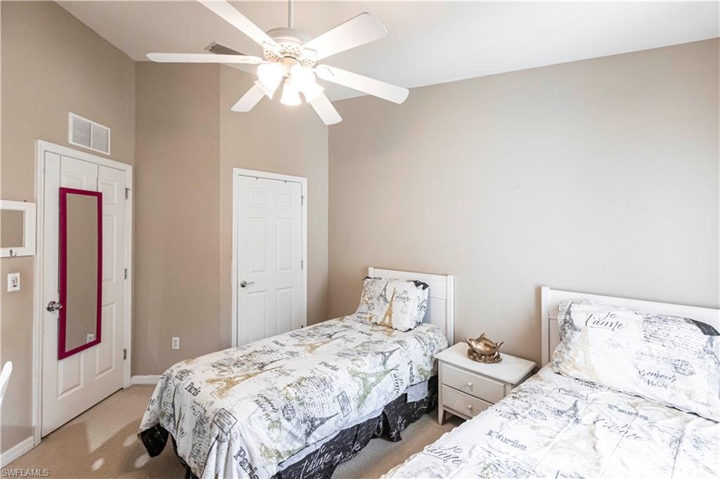 Bedroom with light carpet, a ceiling fan, and vaulted ceiling