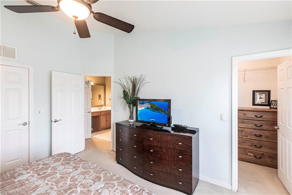 Bedroom with light carpet, ensuite bath, and ceiling fan