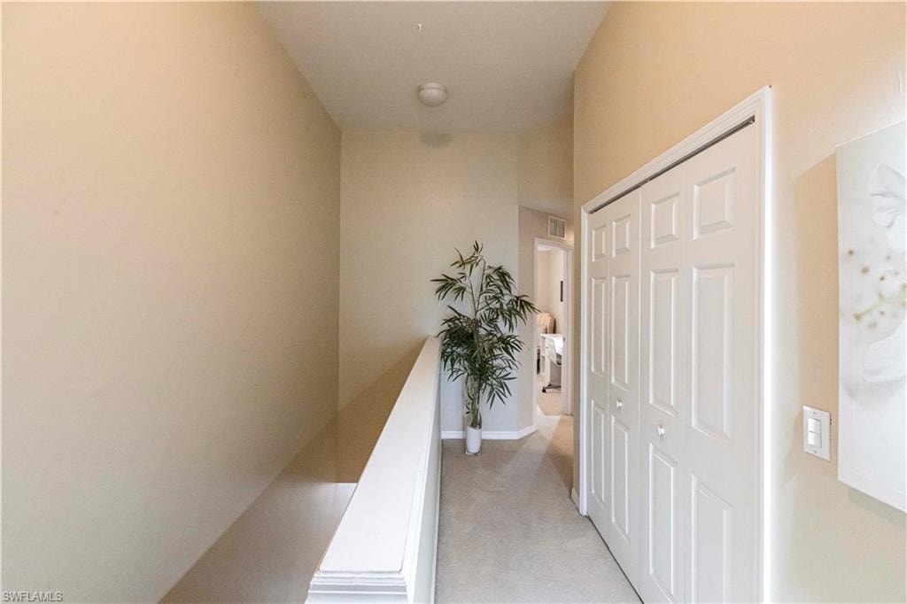 Hallway featuring light colored carpet and baseboards