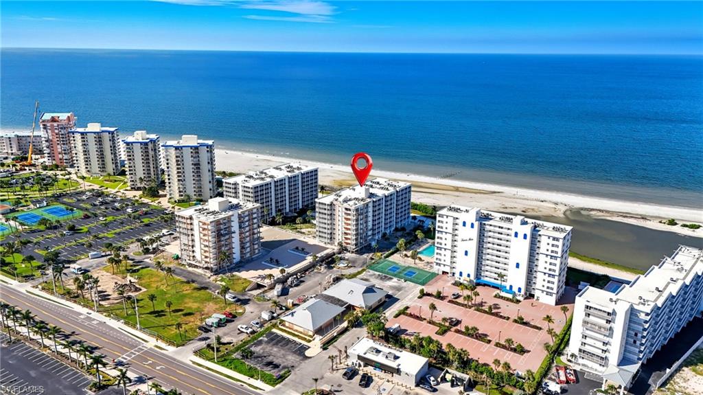 Oceanfront condominium building featuring multiple balconies, a coastal setting, and nearby tennis courts